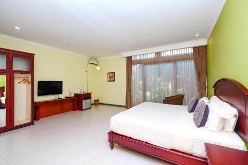 a bedroom with a bed and a flat screen tv at Maharani Guest House in Yogyakarta