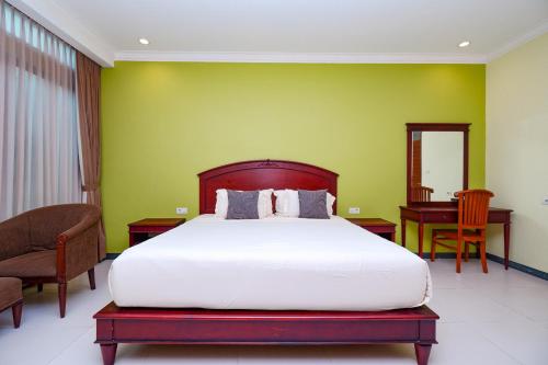 a bedroom with a bed and a green wall at Maharani Guest House in Yogyakarta