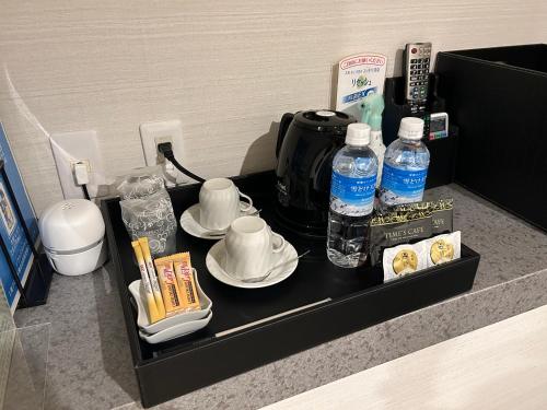 a tray with cups and plates and bottles of water at ホテルアイエス in Yokohama