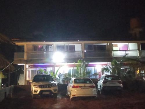 three cars parked in front of a building at night at Gokarna Govekar Sea Facing Rooms in Gokarn