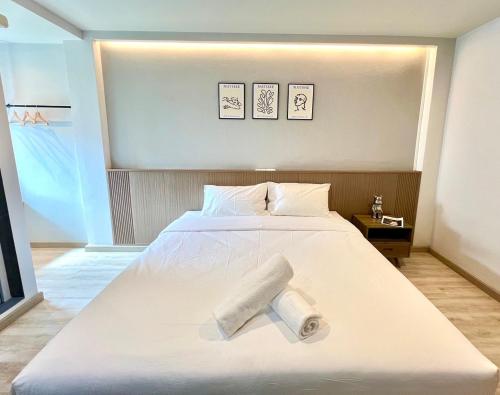 a large white bed with a rolled up towel on it at Bedter Hotel Phang Nga in Phangnga