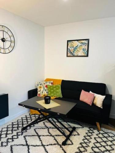 un salon avec un canapé noir et une table dans l'établissement Le Smalto, à Amiens