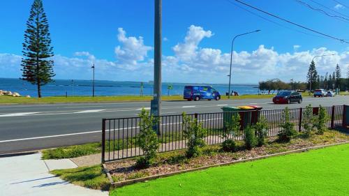 a street with cars driving down a road next to the ocean at Beach View Cottage in Clontarf