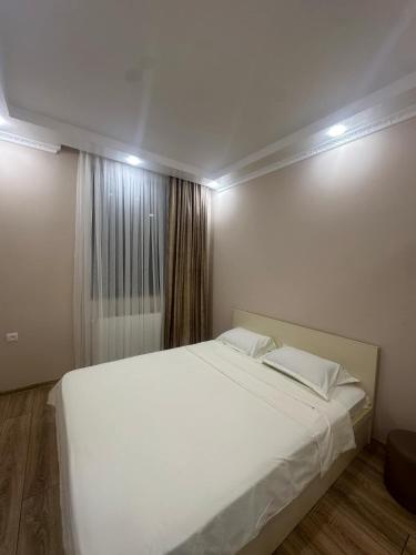 Una cama blanca en una habitación con ventana. en Квартира, en Minda
