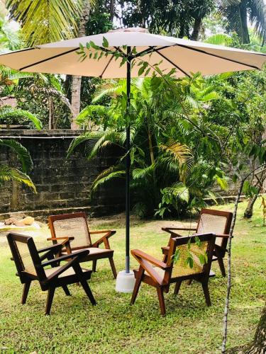 three chairs and a table under an umbrella at The Esence of Sri Lanka in Ahungalla