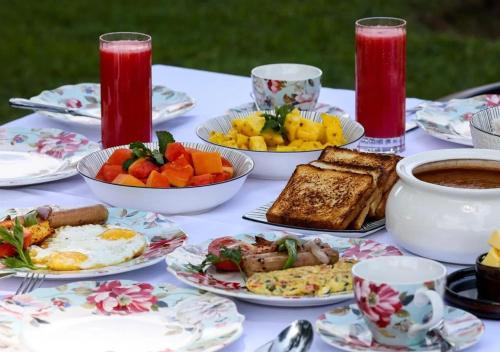 ein Tisch mit Tellern mit Essen und Tassen Kaffee in der Unterkunft Taj Mahal Vintage Villa by VOYE HOMES in Kodaikanal
