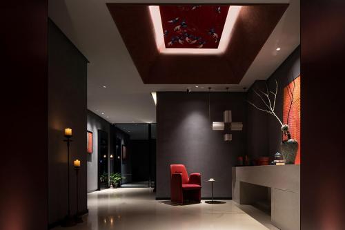 a lobby with red chairs and a ceiling at Qianzitong First Seeing Hotel in Changping