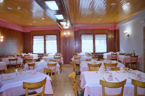 uma sala de jantar com mesas e cadeiras com toalhas de mesa brancas em Hostal Fondevila em Bohí