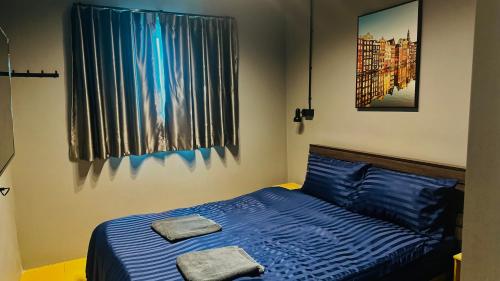 a bedroom with a blue bed with two towels on it at Friends Station Tukkom Hostel & Cafe in Pattaya South