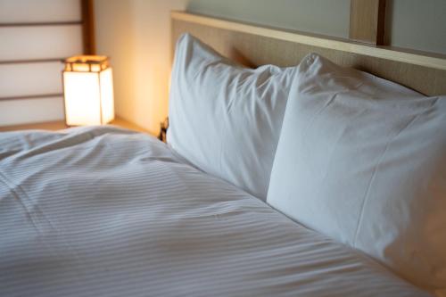 a bed with white sheets and a light next to it at プライベートリゾート伊豆 in Izunokuni