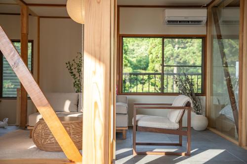 a room with a table and a chair and windows at プライベートリゾート伊豆 in Izunokuni