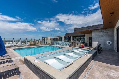 a pool on the roof of a building with chairs at Exceptional 1BD BA-PoolHotTubGymParking- Downtown! in Salt Lake City