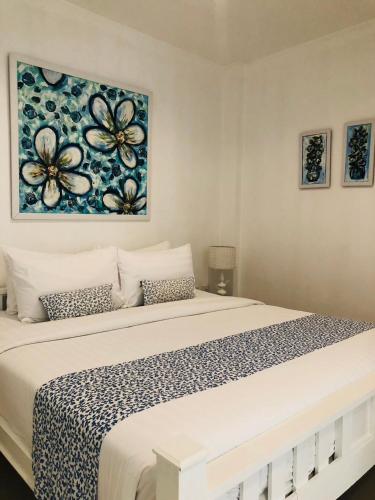 a bedroom with a large bed with a flower painting on the wall at Casa Blanca Boutique Hotel - SHA Plus in Phuket Town