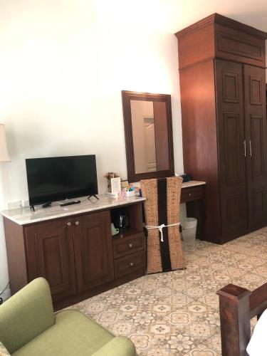 a living room with a television and a desk with a cabinet at Casa Blanca Boutique Hotel - SHA Plus in Phuket Town