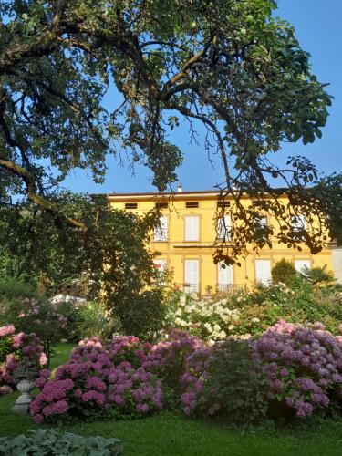 une maison jaune avec des fleurs devant elle dans l'établissement B&B Cantine Marchesi, à San Bernardo