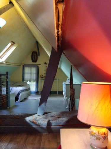 Cette chambre mansardée comprend un lit et une table avec une lampe. dans l'établissement Maison à la campagne, à Courtonne-la-Meurdrac