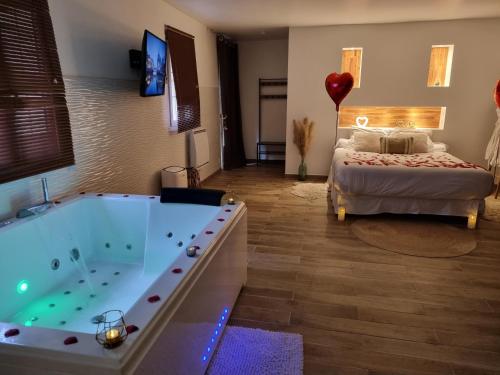 a large bathroom with a tub and a bed and a room at Suite de charme avec JACUZZI illimité et jardin privatif in Saint-Prix