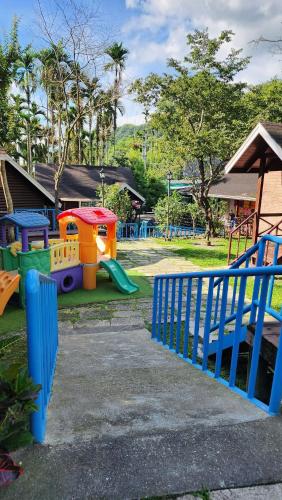 a park with a playground with play equipment and a blue fence at 杉溪鹿莊園-溪頭獨棟式小木屋 & 如需溜滑房型請選請選家庭房 in Lugu