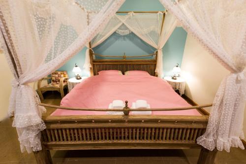 1 dormitorio con cama con dosel y sábanas rosas en BB&B Hotel, en Fang