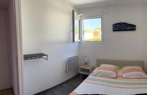 une chambre blanche avec un lit et une fenêtre dans l'établissement Appartement T3 Vue Mer La Corniche Sète, à Sète