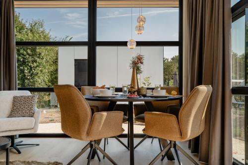 a dining room with a table and chairs and a large window at MarinaPark Residentie Bloemendaal in Vogelenzang