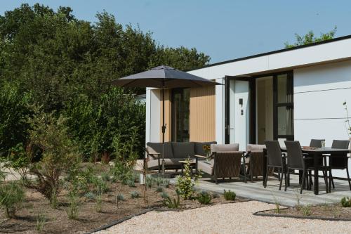 a patio with a table and chairs and an umbrella at MarinaPark Residentie Bloemendaal in Vogelenzang