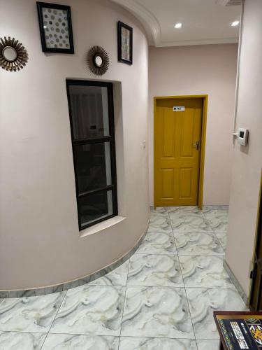 a hallway with a yellow door and a tile floor at Pomona BB House in Harare