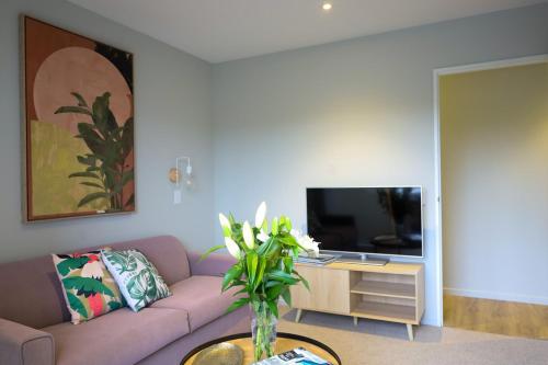 a living room with a purple couch and a tv at New Brighton Pier Retreat - in Christchurch