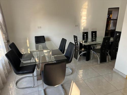 a dining room with a glass table and black chairs at Pomona BB House in Harare