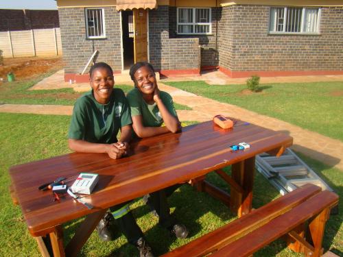 two men are sitting at a picnic table at Pomona BB House in Harare