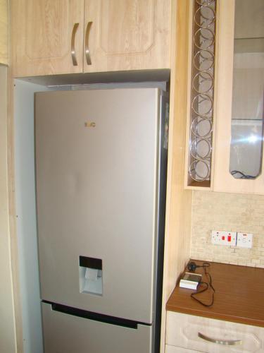 a white refrigerator in a kitchen with cabinets at Pomona BB House in Harare