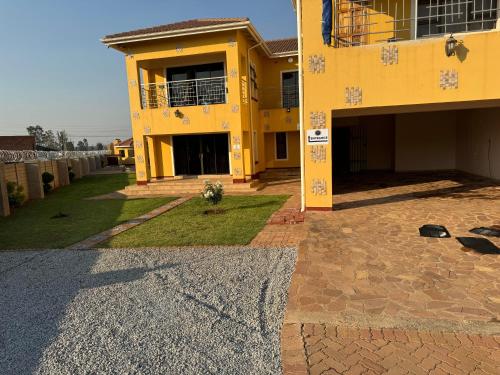 a yellow house with a courtyard in front of it at Pomona BB House in Harare