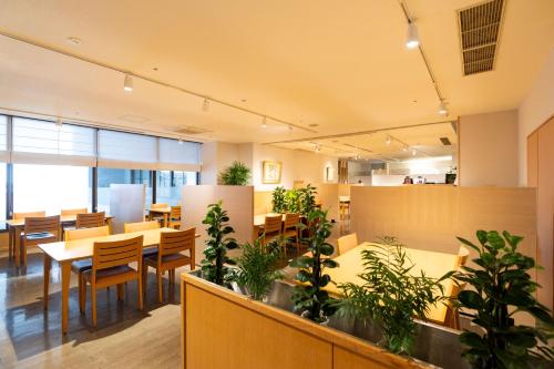 a restaurant with tables and chairs and potted plants at Onomichi Kokusai Hotel in Onomichi