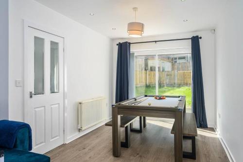 a room with a ping pong table in front of a window at Spacious 4Bed Home, Sleeps 10, Pool Table, Parking, Perfect For Groups in Manchester