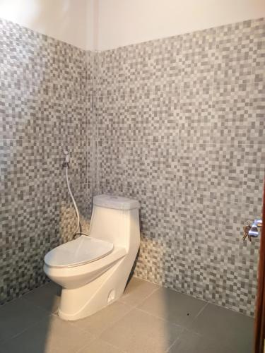 a bathroom with a toilet in a tiled wall at Tata Surf Hostel in Kuta Lombok