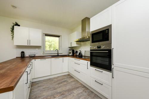 a white kitchen with white cabinets and a window at Chata Henry in Krásná