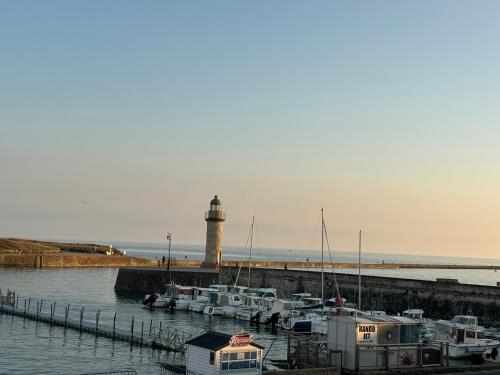 a group of boats docked at a dock with a lighthouse at Vue panoramique PORT et OCEAN in Saint-Gilles-Croix-de-Vie