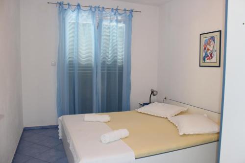 a bedroom with a bed and a window with blue curtains at Vidoni - apartmani Roza in Zastražišće