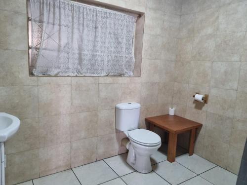 a bathroom with a toilet and a sink and a window at Emerald Guesthouse in Kempton Park