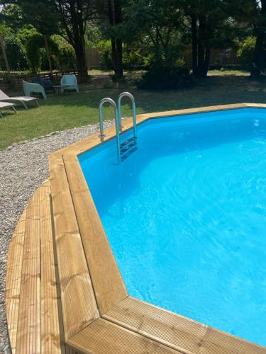 Una piscina con un banco de madera al lado. en Le Cocon de Curson chambre d'hôtes, en Chanos-Curson