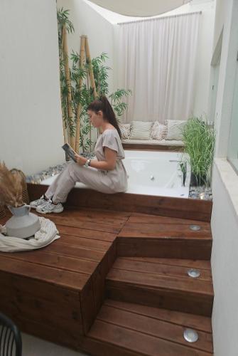 a woman sitting on a wooden deck with a bath tub at Atlantis Boutique City Hotel in Rhodes Town