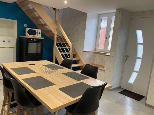 une cuisine avec une table et des chaises ainsi qu'un escalier dans l'établissement Jolie maison rénovée, à Poulangy