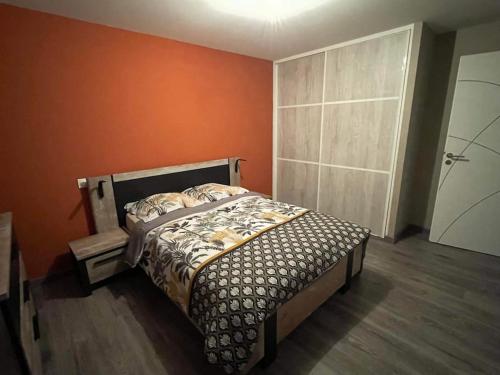 une chambre avec un lit avec un mur orange dans l'établissement Jolie maison rénovée, à Poulangy