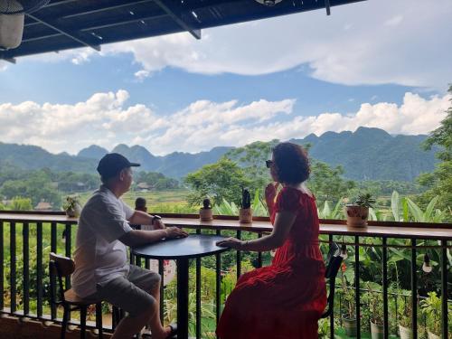a man and a woman sitting at a table on a balcony at Inh La Home Pu Luong in Pu Luong