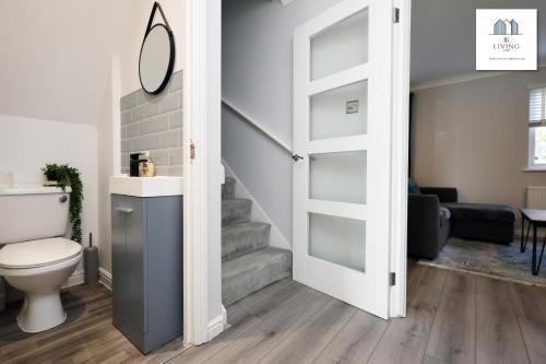 La salle de bains est pourvue de toilettes et d'un escalier. dans l'établissement Spacious 3 Bed Home In The Heart Of Bridgend - By EKLIVING LUXE Short Lets & Serviced Accommodation, à Bridgend