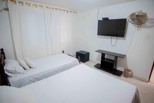 a hotel room with two beds and a flat screen tv at Casa Nora Alojamiento Entero, 4 Habitaciones Capacidad Máxima 9 huéspedes in Ríohacha
