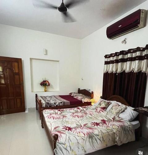 a bedroom with two beds and a ceiling fan at Cape-Cottage in Nāgercoil