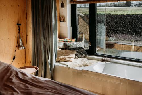 a bathroom with a bath tub next to a window at Familie Buitenhuys Countryside Home with wide landscape views from the bathtub in Oosterleek