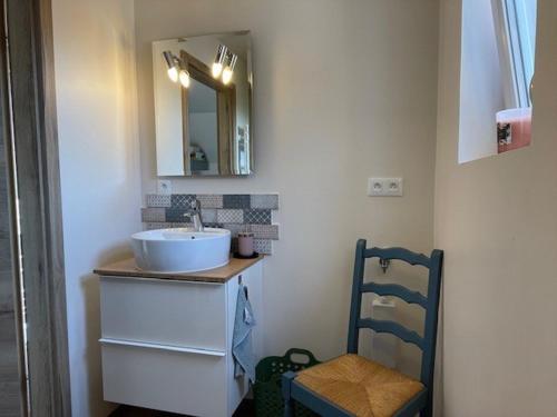 une salle de bain avec un lavabo, un miroir et une chaise dans l'établissement Appartement et terrasse privée, à Ingolsheim