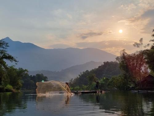 a person is standing on a boat in a river at Inh La Home Pu Luong in Pu Luong
